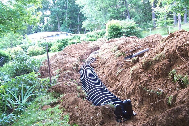 Corrugated drain pipe in a hillside trench between garden beds